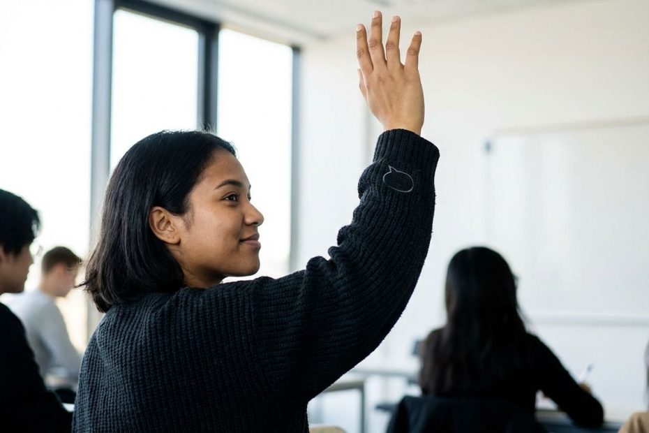 Student raising a hand to share a point during a classroom discussion.